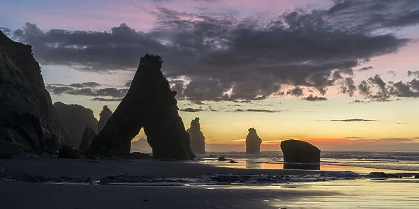 Sunset at the Three Sisters beach, with Mt Taranaki seen through the rock cave