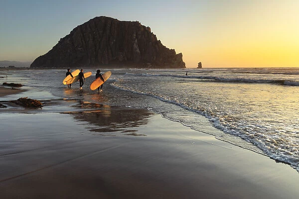 Surfer at Morro Strand State Beach with Morro Rock, Morro Bay, California, USA