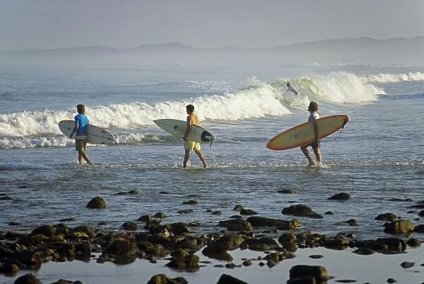 Surfers head into the surf at Mancora on the northern coast of Peru