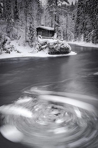 Surreal vortex of icy water surrounding the snowy landscape near Myllykoski old mill, Oulanka National Park, Lapland, Finland