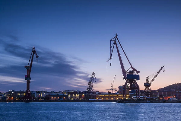 Sweden, Vastragotland and Bohuslan, Gothenburg, shipyard crane, city skyline, dusk