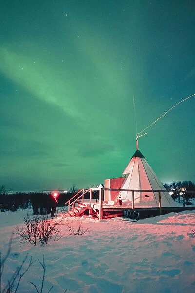 Swedish Lapland, Abisko National Park. Northern Lights over a typical teepee in the snow, winter. Arctic Circle