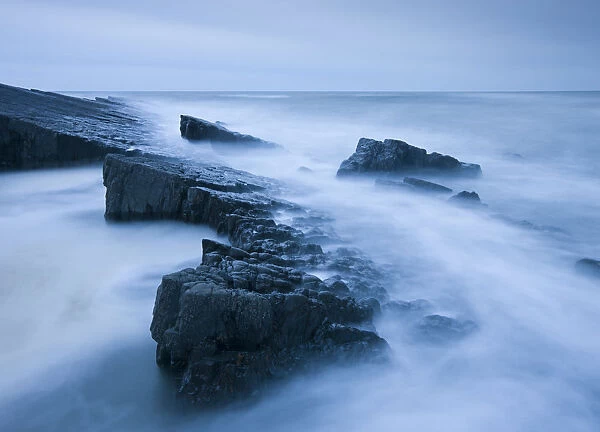 Swiling tide around jagged rocks on Spekes Mill Mouth beach, Hartland, Devon, England