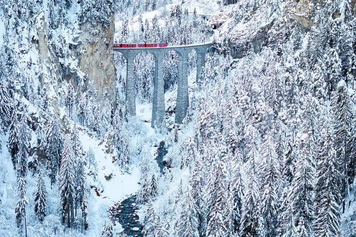Framed Print : Swiss red train crossing Landwasser viaduct above a frozen river in the snowy landscape, Filisur, Graubunden canton, Switzerland