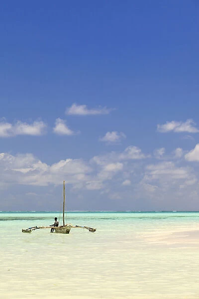 Tanzania, Zanzibar, Unguja, Jambiani. A man sits on his boat