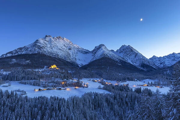 Tarasp Castle and the moon at twilight. Tarasp, Lower Engadine, Canton of Grisons