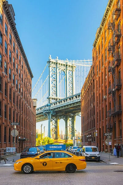 Taxi passing under the Manhattan bridge with the Empire state building framed in the
