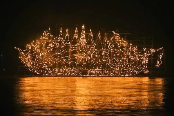 Thailand, Nakhon Phanom, That Phanom. A Fire Boat drifts on the Mekong River during the Illuminated Boat Procession. The fire boats are giant bamboo towers decorated with lanterns in religious motifs to celebrate the end of the Buddhist