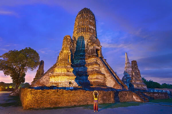 Thailand, Phra Nakhon Si Ayutthaya, Ayutthaya, Wat Chai Watthanaram illuminated at night, girl with camera. UNESCO World Heritage site (MR)