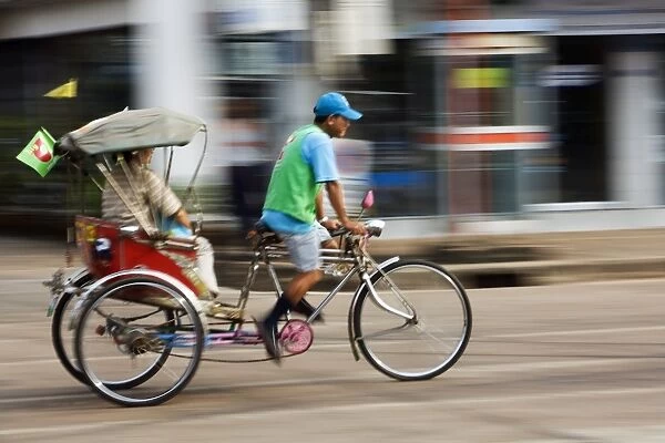 Thailand, Sakhon Nakhon, Sakhon Nakhon. A saamlaw (three wheeled pedicab) driver peddles his passengers through the streets of