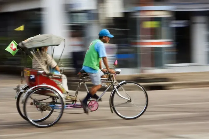 Framed Print : Thailand, Sakhon Nakhon, Sakhon Nakhon. A saamlaw (three wheeled pedicab) driver peddles his passengers through the streets of