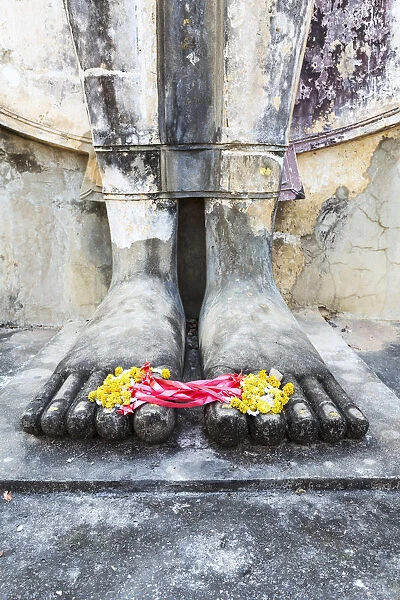 Thailand, Sukhothai Historical Park. Detail of Buddha feet with floreal offering
