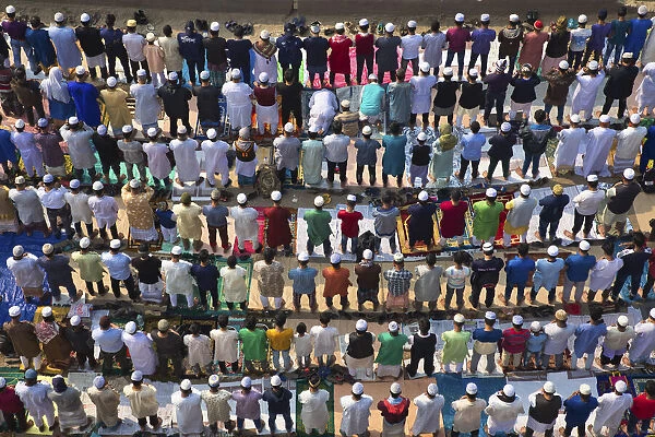 Thousands of Muslims kneel in the middle of a busy road junction to pray