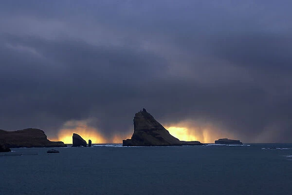 Tindholmur islet and Drangarnir sea stacks in a stormy day at sunset. Island of Vagar. Faroe Islands