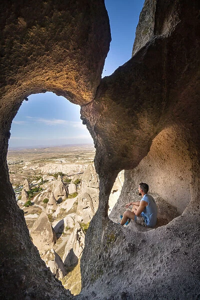 Tourist admiring Capadocias landscape from a tuff cave
