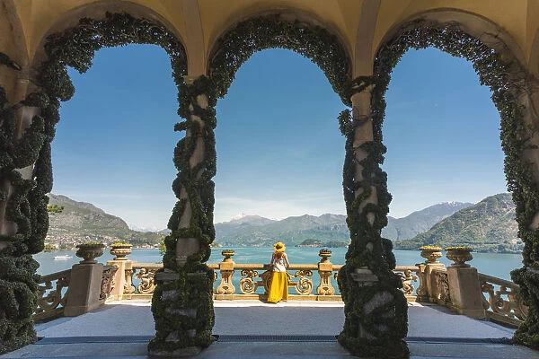 Tourist admiring Como lake view from the loggia of the villa del Balbianello on Punta