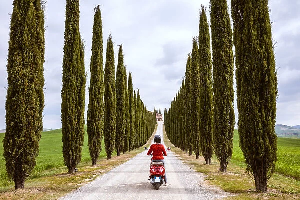 Tourist riding an italian vespa motorcycle in the countryside. Val d Orcia, Tuscany