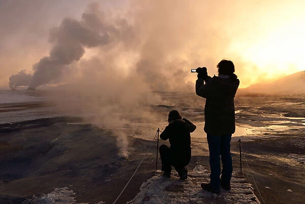 Tourists photograph Hot sulphur springs near Reykjavik, Iceland