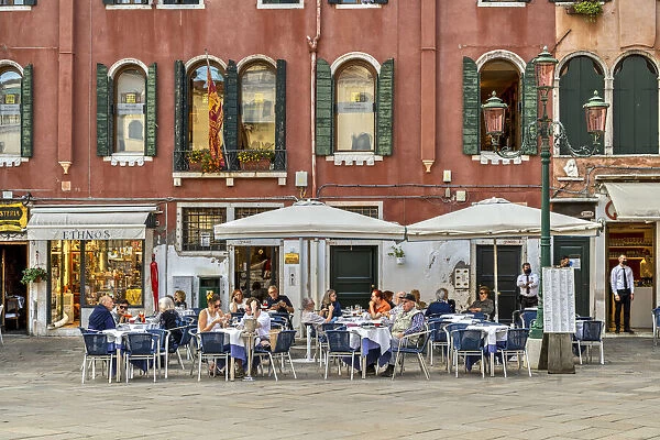 Tourists seated in an outdoor cafe in a small square of Venice, Veneto, Italy