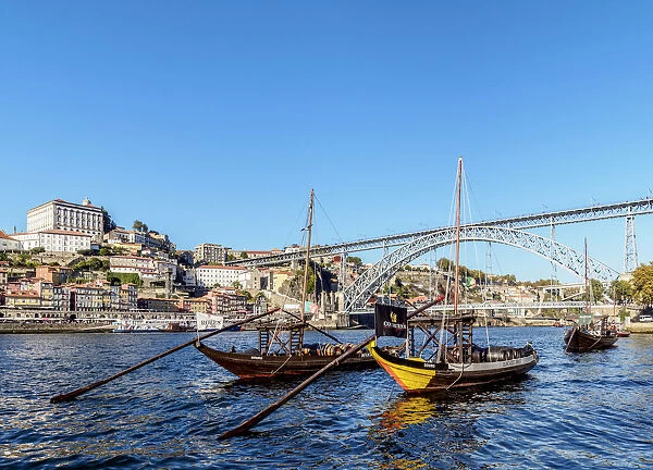 Traditional boats on Vila Nova de Gaia bank of Douro River, Dom Luis I Bridge in the