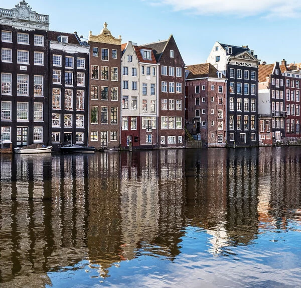 Traditional buildings along the Damrak reflected in the canal, Amsterdam, the Netherlands