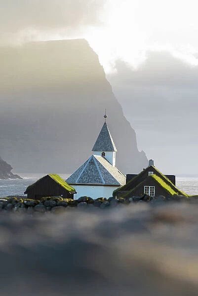 Traditional church and houses with grass roof in the village of Vidareidi at sunset, Vidoy island, Faroe islands, Denmark