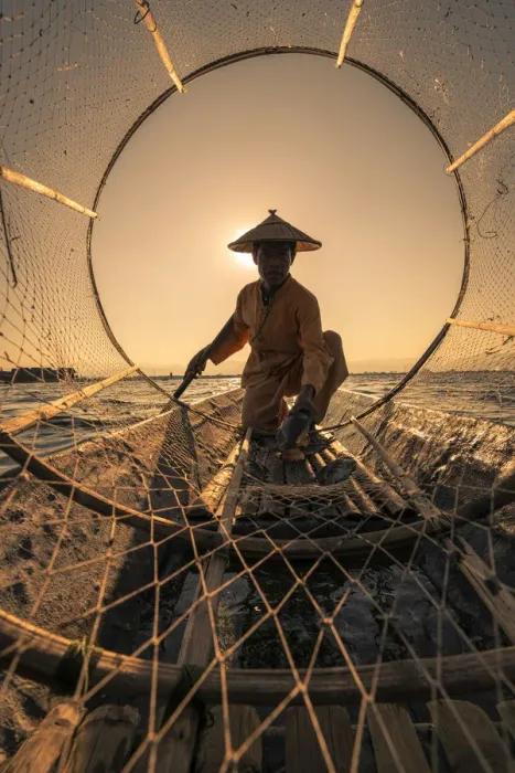 Framed Print : Traditional fisherman viewed through conical fishing net collecting fish on a boat Framed Print : Traditional fisherman viewed through conical fishing net collecting fish on a boat