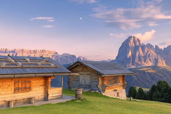 Traditional huts at sunset with Sassolungo and Sella Group in the background