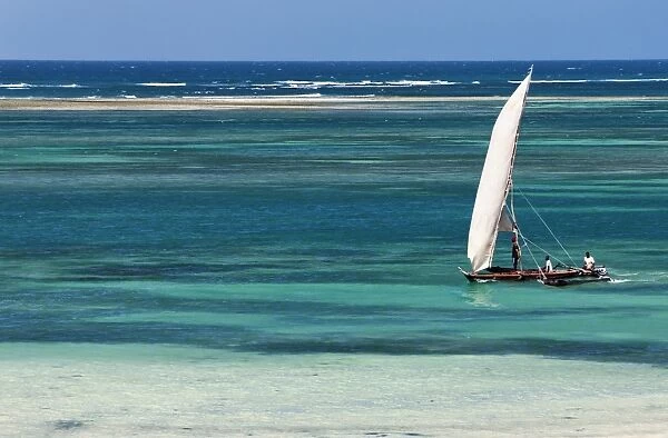 A traditional outrigger canoe sails close to the shore at Diani Beach