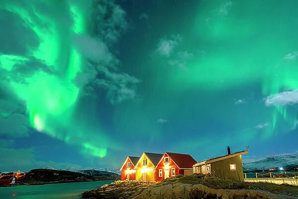 Traditional rorbu hit by Northern Lights in winter, Sommaroy, Troms og Finnmark, Norway