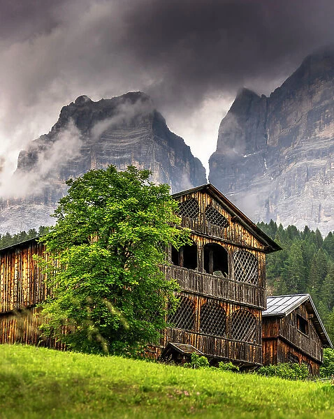 Traditional rustic wooden houses in the village of Coi in Val di Zoldo, with Mount Pelmo behind. Zoldo valley, Cadore, Belluno province, Veneto, Italy