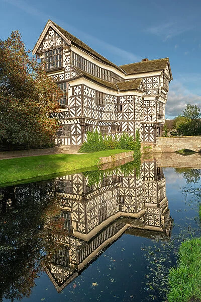 Tudor manor Little Moreton Hall, reflected in its moat, Congleton, Cheshire, England. Autumn (October) 2023