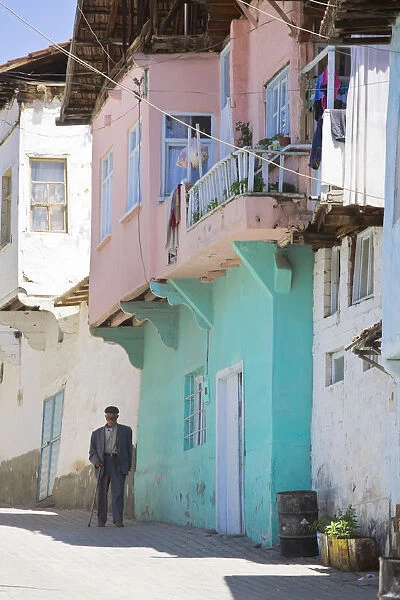 Turkey, Eastern Turkey, Malatya, Gunduzbey Village, Man walking along street past
