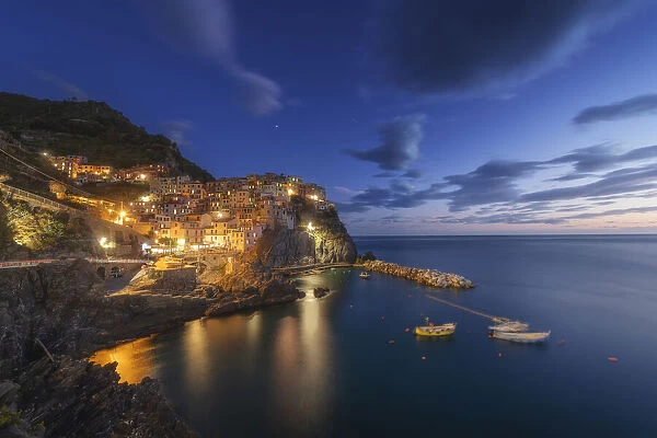 Twilight in Manarola, Cinque Terre, the most beautiful moment of the day when the lights of the town come