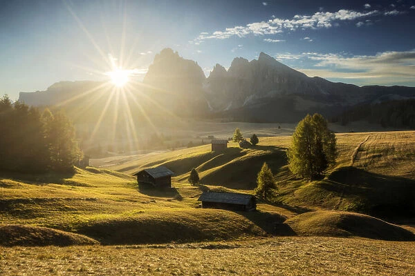 Some typical cabins in the meadows of the Alpe di Siusi (Seiser Alm) during an early autumn sunrise, with the Sassolungo and Sassopiatto in the background. Dolomites, Italy