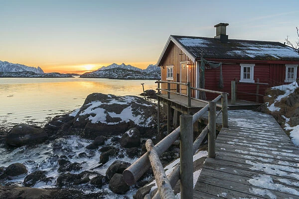 Typical fishermen red house on the sea at dawn in winter. Svolvaer, Nordland county