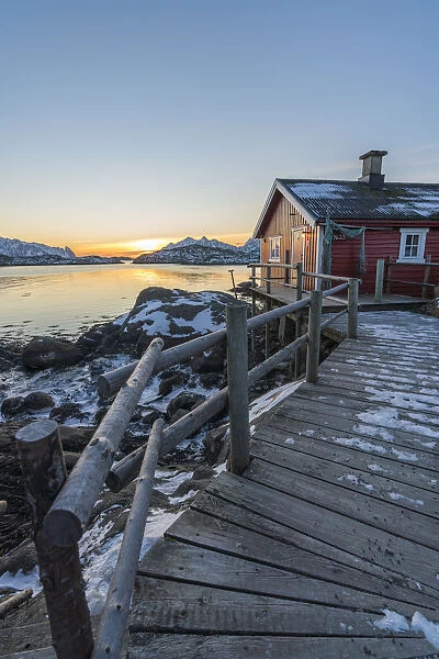 Typical fishermen red house on the sea at dawn in winter. Svolvaer, Nordland county