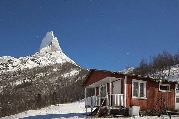 A typical house of fishermen called Rorbu frames the snowy Stetind mountain under