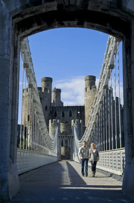 Framed Print : UK, North Wales; Conwy. Couple on the elegant Suspension Bridge built by Thomas Telford across the Conwy River to the imposing Framed Print : UK, North Wales; Conwy. Couple on the elegant Suspension Bridge built by Thomas Telford across the Conwy River to the imposing