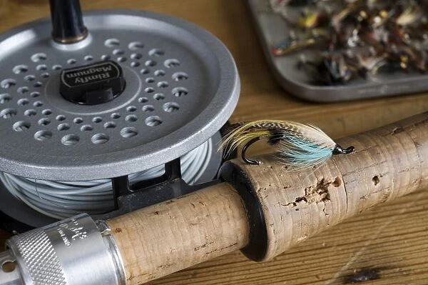 UK. A salmon fly stuck into the cork handle of a fly fishing rod