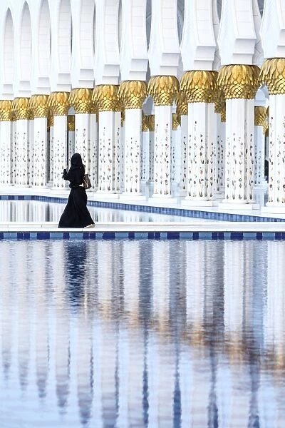 United Arab Emirates, Abu Dhabi. Arabic woman walking inside Sheikh Zayed Grand Mosque