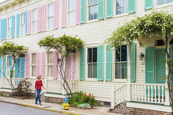 USA, Georgia, Savannah, Woman walking past a row of colourful houses