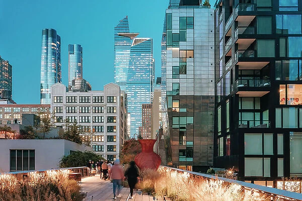 USA, New York City, people walking on the High Line between Chelsea and Hudson Yards with the Edge building in the background