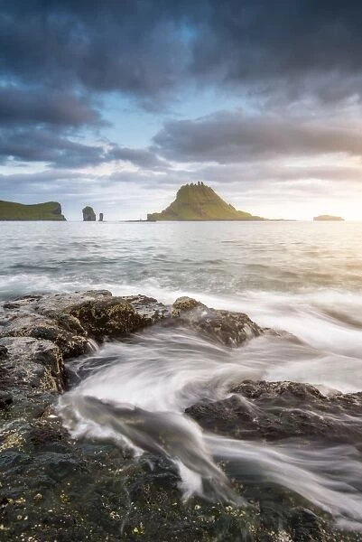 Vagar island, Faroe Islands, Denmark. Coastal rocks with Tinholmur islet at the background