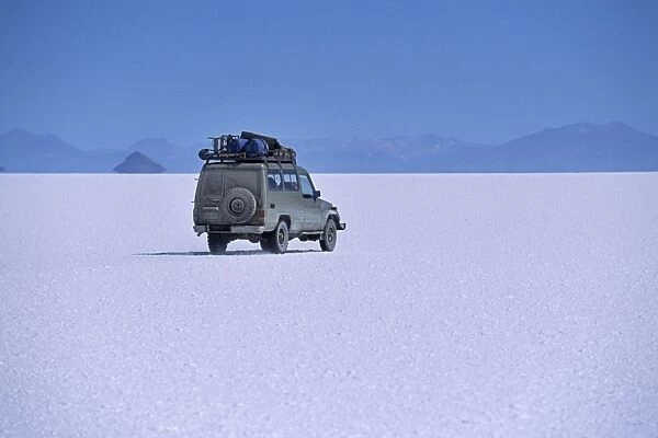 A vehicle drives across the crusted salt of the Salar de Uyuni
