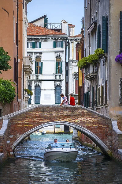 Venice, Veneto, Italy. Two boys sitting on a canals bridge