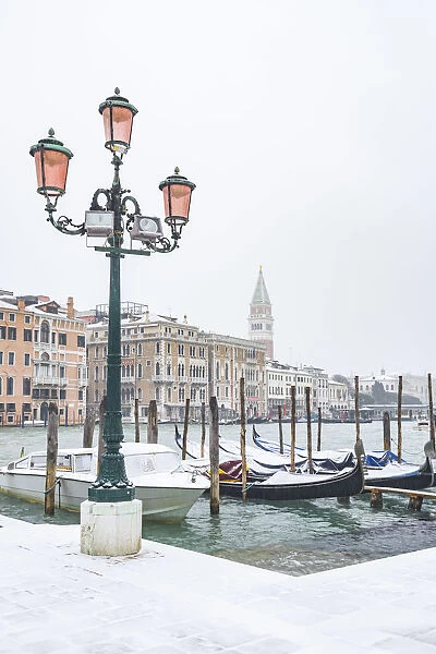 Venice, Veneto, Italy. Gondolas on the waterfront with snow in Dorsoduro