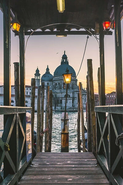 Venice, Veneto, Italy. Salute (St Mary of Health) Basilica and wooder pier at dusk