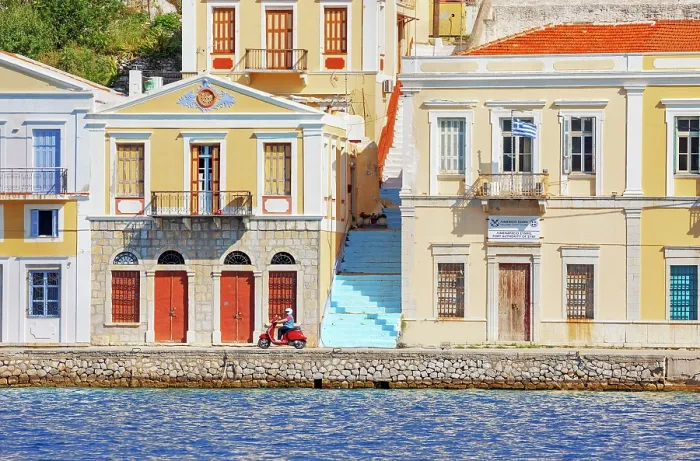 Framed Print : Vespa driving along Gialos Harbour quay, Gialos, Symi Island, Dodecanese Islands, Greece Framed Print : Vespa driving along Gialos Harbour quay, Gialos, Symi Island, Dodecanese Islands, Greece