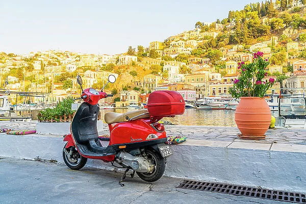 A vespa scooter by the colourful harbour in Symi, Dodecanese Islands, Greece